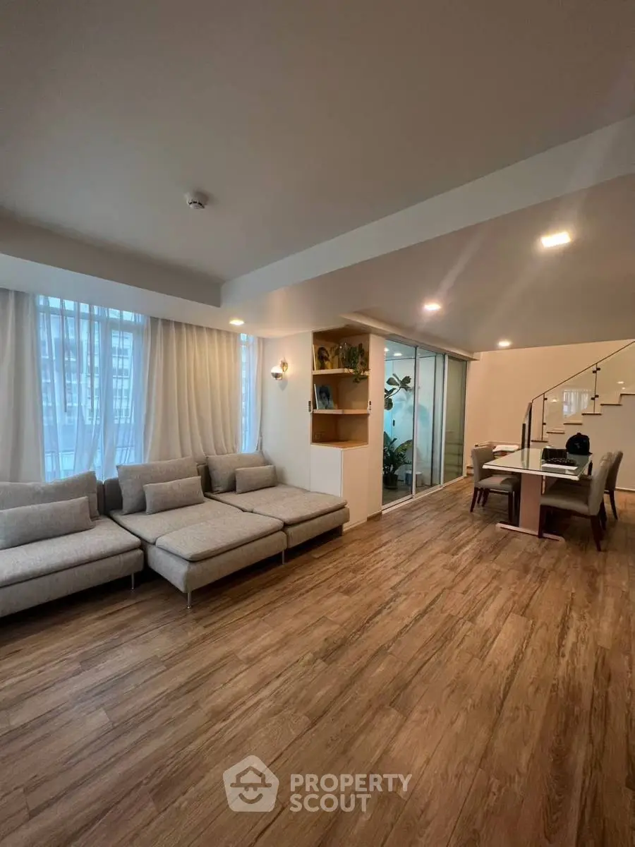Spacious modern living room with elegant wooden flooring and cozy seating area.