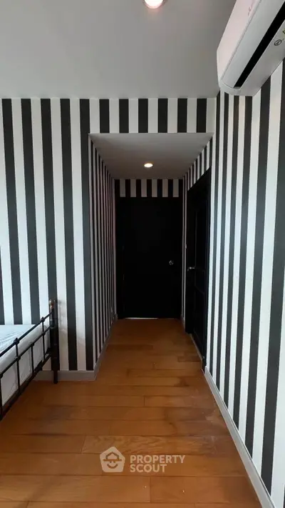 Stylish bedroom with bold striped walls and wooden flooring, featuring modern air conditioning.