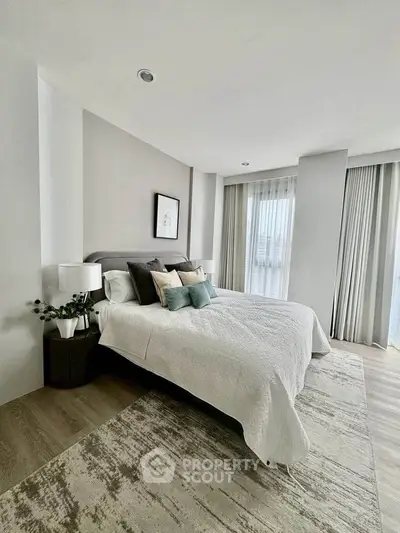 Modern bedroom with stylish decor and large windows offering natural light