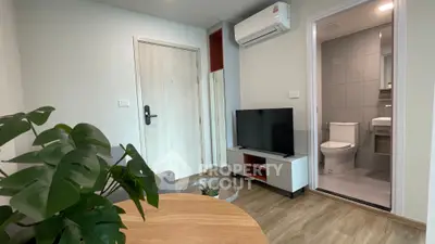 Modern living room with TV and air conditioning, adjacent to a compact bathroom.