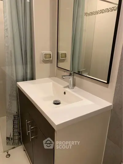 Modern bathroom with sleek vanity and large mirror, featuring elegant design and neutral tones.