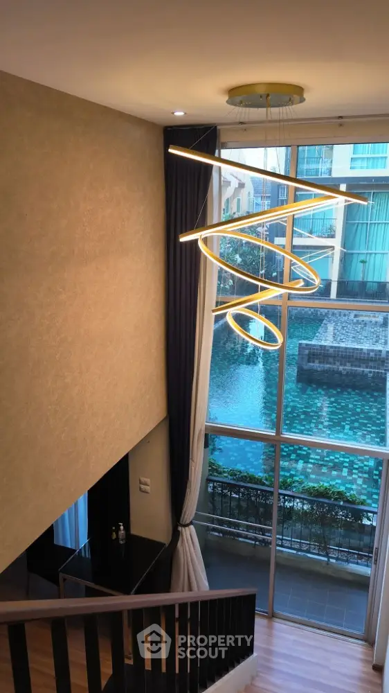 Luxurious staircase with modern chandelier overlooking stunning pool view