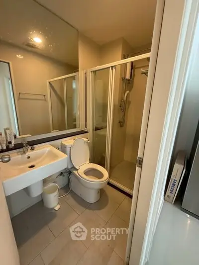 Modern bathroom with glass shower and sleek fixtures in contemporary apartment.