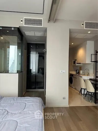 Modern studio apartment with sleek kitchen and cozy bedroom area, featuring contemporary design and efficient layout.
