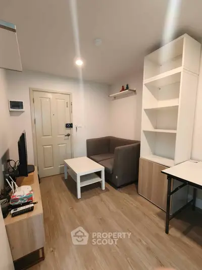 Cozy living room with modern furniture and wooden flooring in a compact apartment.