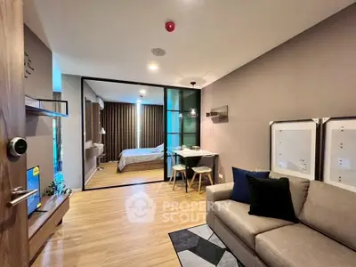Modern open-plan living room with cozy seating and stylish decor, leading to a chic bedroom.