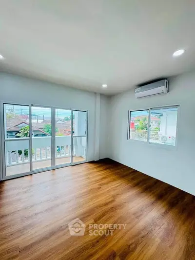 Spacious living room with large windows and wooden flooring, offering a bright and airy atmosphere.
