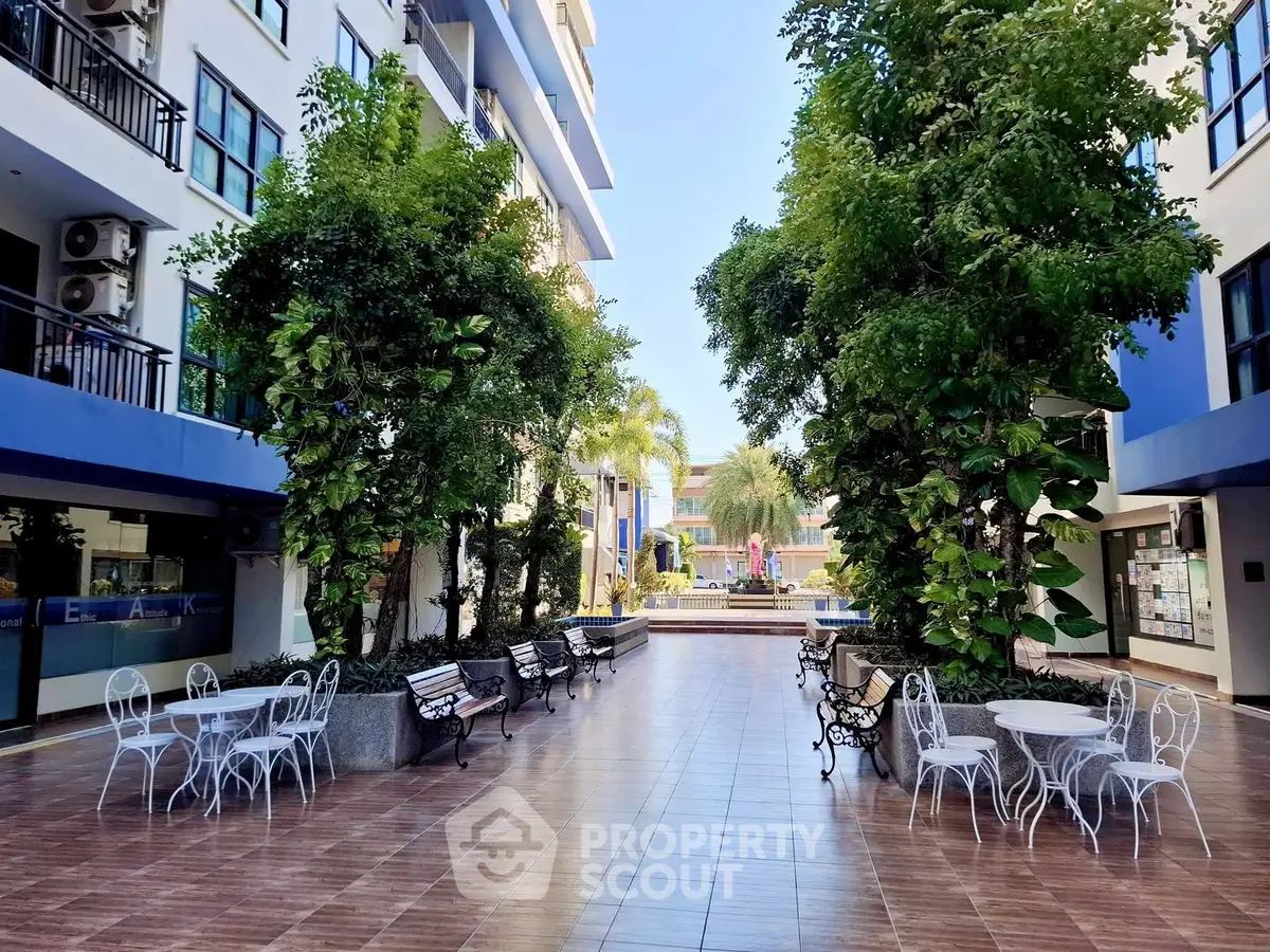 Charming courtyard with lush greenery and seating in modern residential complex.