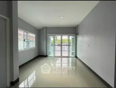 Spacious unfurnished room with large windows and glossy tiled floor, perfect for customization.