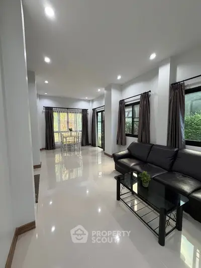 Spacious modern living room with sleek black sofa and large windows for natural light.