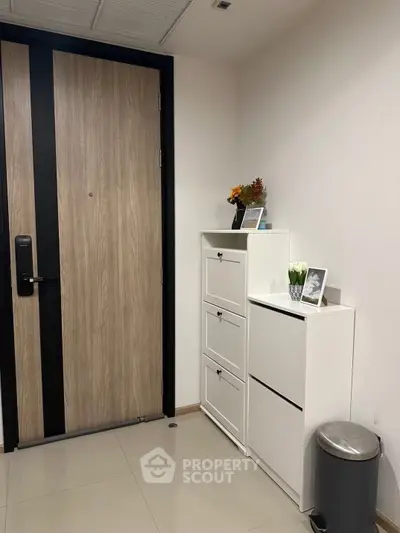Modern apartment entrance with sleek wooden door and stylish white storage cabinets.