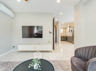 Modern living room with sleek TV setup and open kitchen layout