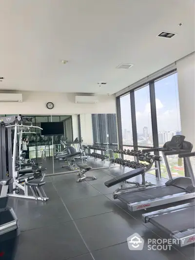 Spacious modern gym with city view and state-of-the-art equipment in luxury high-rise building.