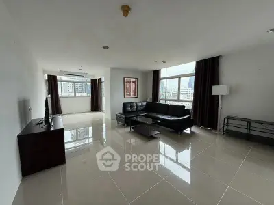 Spacious modern living room with sleek black sofa and large windows offering city views.