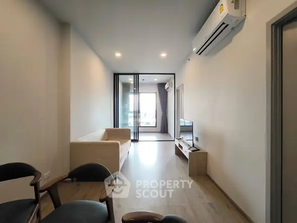 Modern living room with sleek design and air conditioning, leading to a cozy bedroom.