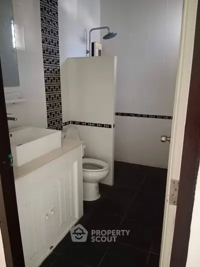 Modern bathroom with sleek black and white tile design and contemporary fixtures.