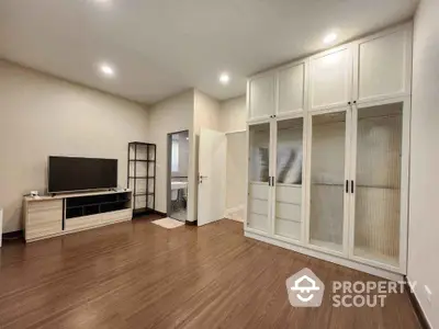 Spacious modern living room with built-in wardrobe and sleek wooden flooring.