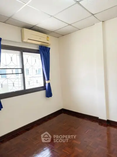 Bright empty room with parquet flooring and air conditioning