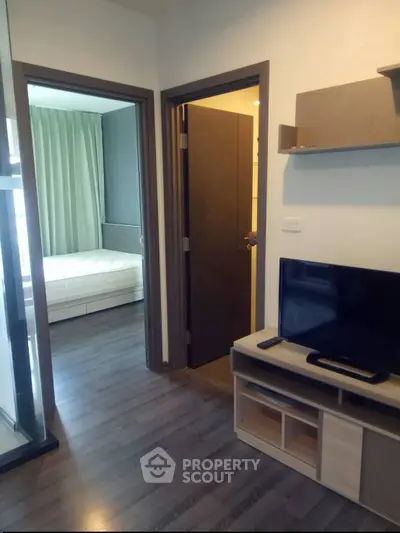 Modern apartment interior with bedroom and living area featuring sleek wooden flooring and contemporary furniture.