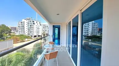 Spacious balcony with modern glass railing and outdoor seating, offering a stunning view of contemporary buildings.