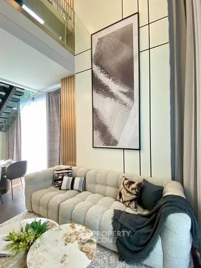 Luxurious modern living room with stylish decor and plush sofa in a high-ceiling apartment.