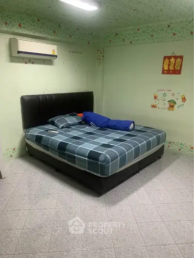 Cozy bedroom with air conditioning and decorative wall accents, featuring a comfortable bed and tiled flooring.