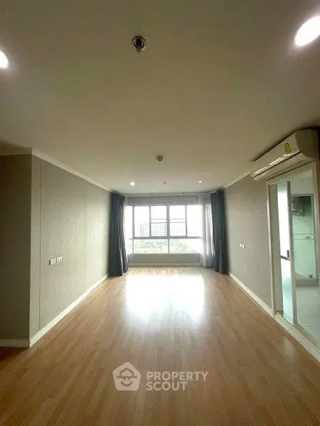 Spacious empty living room with large windows and wooden flooring in modern apartment.