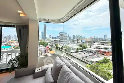Stunning cityscape view from modern living room with large corner window and cozy sofa.