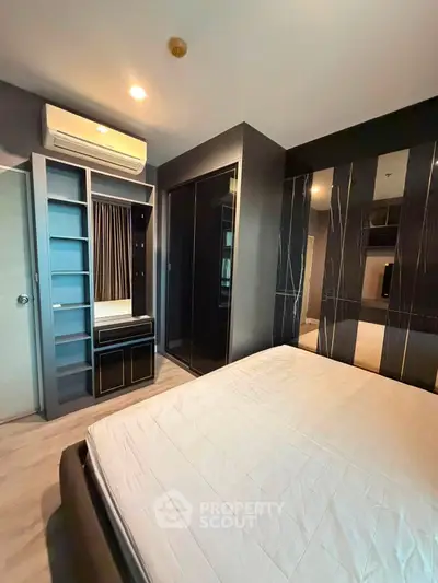 Modern bedroom with sleek black accents and built-in wardrobe in a stylish apartment.