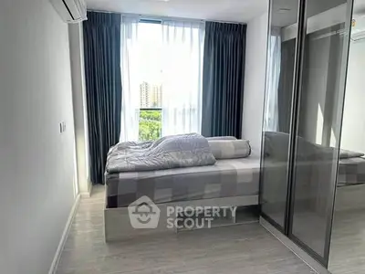 Modern bedroom with large window and mirrored wardrobe in a high-rise apartment.