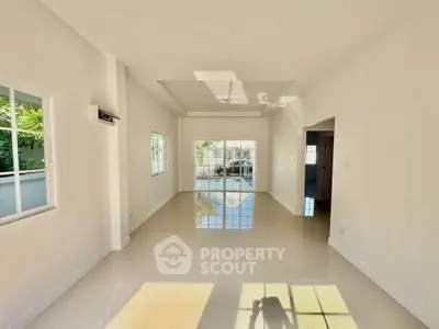 Spacious sunlit living room with large windows and glossy tiled floors in modern home.