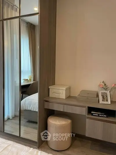 Elegant bedroom with mirrored wardrobe and stylish vanity in modern apartment.