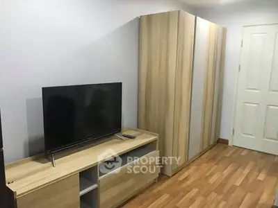 Modern bedroom with sleek wooden furniture and flat-screen TV, perfect for cozy living.