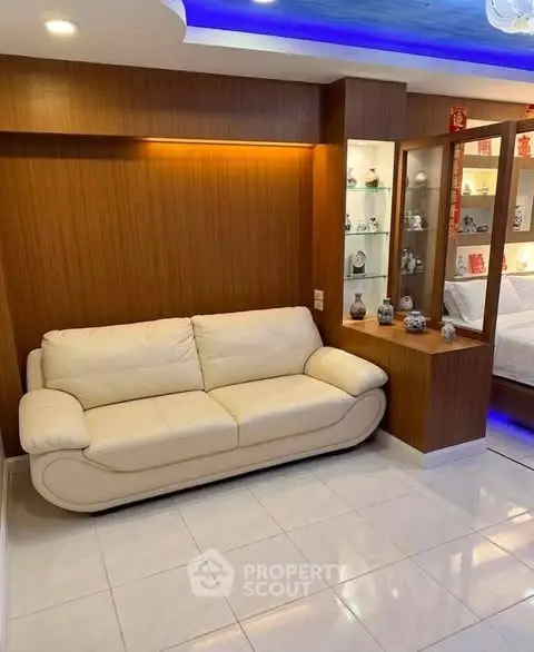 Modern living room with elegant white sofa and decorative shelving, featuring warm wooden accents and ambient lighting.