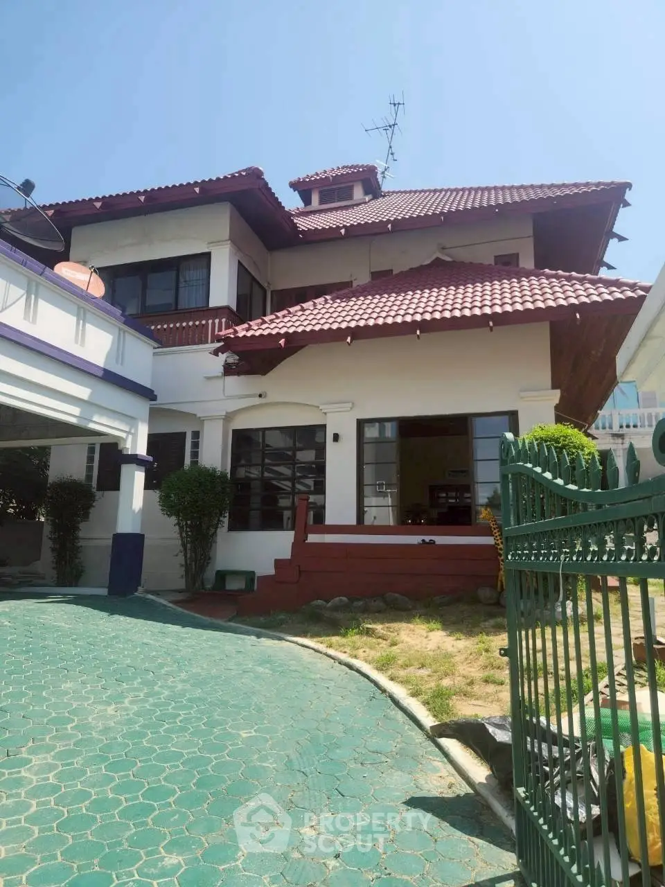 Charming two-story house with red-tiled roof and spacious driveway, perfect for family living.