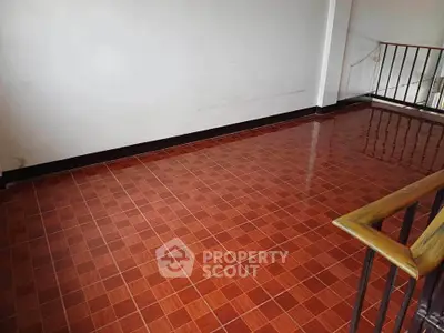 Spacious tiled interior area with wooden railing, ideal for versatile use in a residential property.