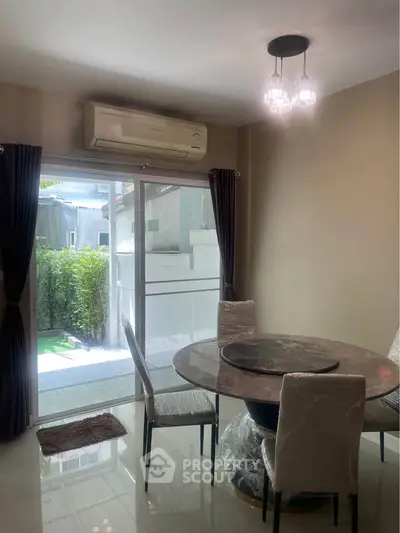 Elegant dining area with round table and garden view, featuring modern lighting and air conditioning.