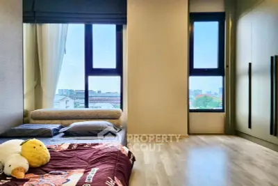 Spacious bedroom with large windows offering stunning city views and modern decor.