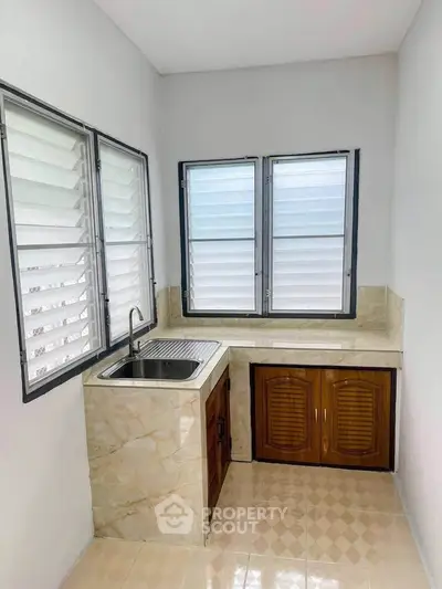 Compact kitchen with marble countertop and dual windows for natural light