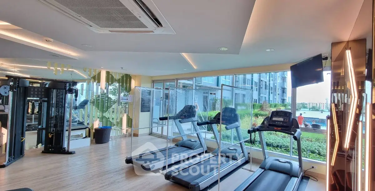 Modern gym with treadmills and large windows offering scenic views in a luxury residential building.