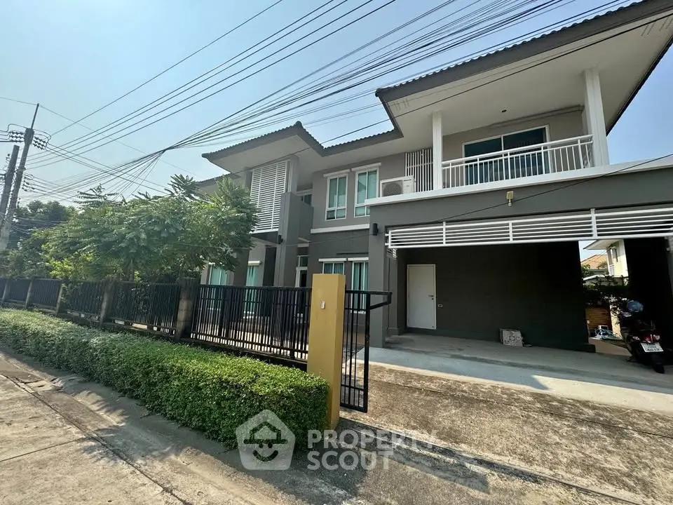 Modern two-story house with spacious balcony and gated driveway in a suburban neighborhood.