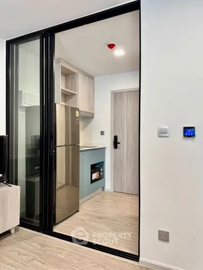 Modern kitchen with sleek appliances and sliding glass door in stylish apartment.