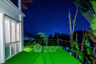 Stunning night view from a spacious balcony with lush greenery and city lights.