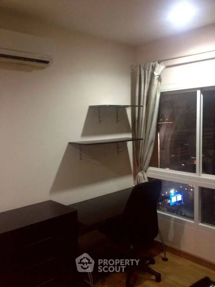 Cozy study room with desk, chair, and shelves by a window with city view.