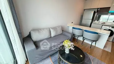 Modern living room with cozy sofa and stylish kitchen area in open layout apartment.