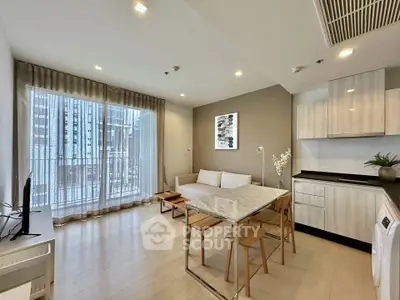 Modern open-layout living room with kitchen, featuring sleek furniture and large windows.