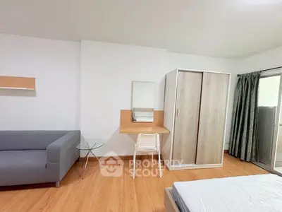 Modern bedroom with sleek furniture and wooden flooring, featuring a wardrobe, desk, and comfortable sofa.