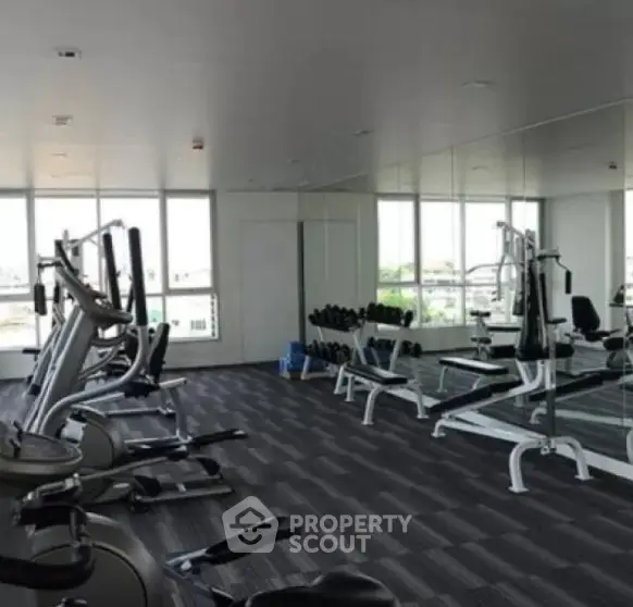 Spacious modern gym with large windows and fitness equipment in a real estate property.