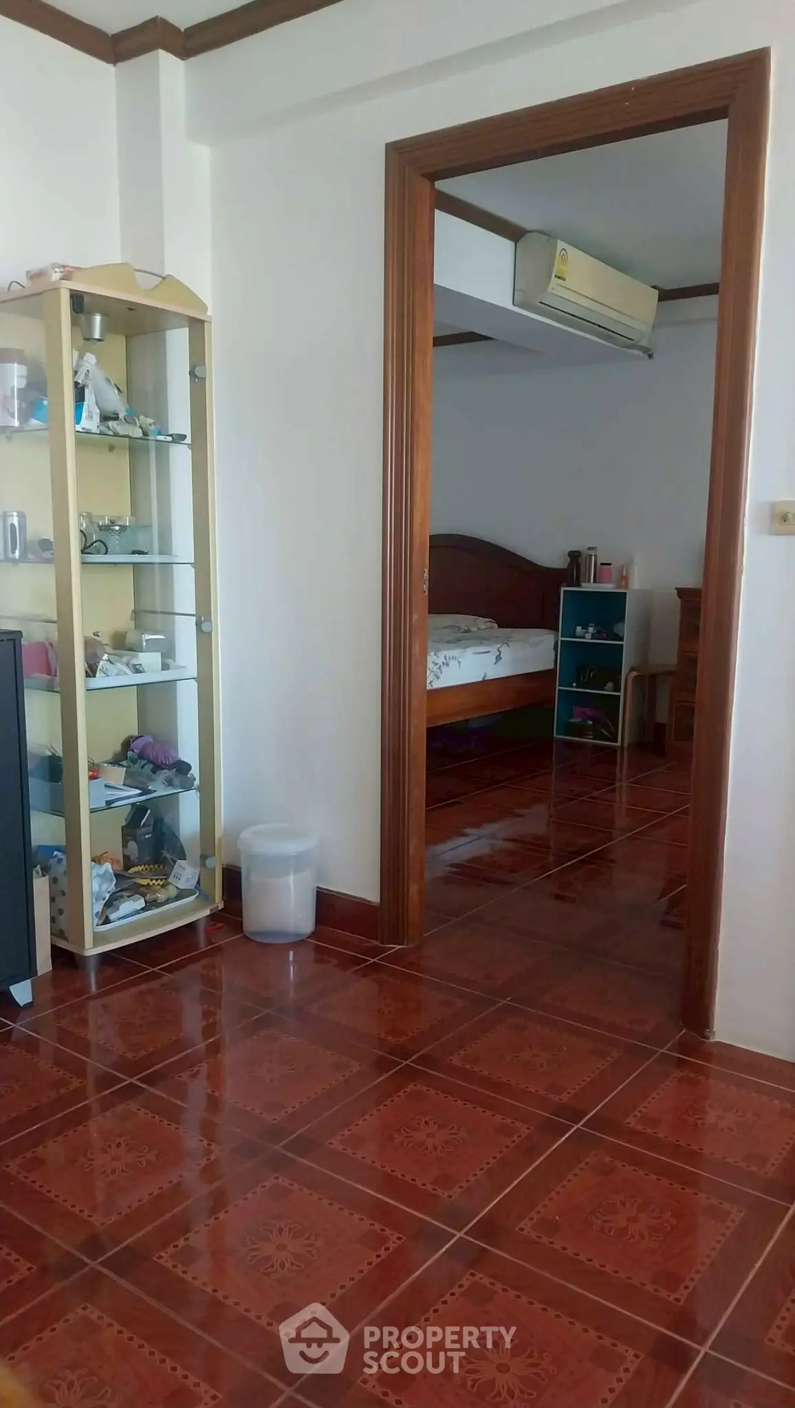 Spacious bedroom with wooden flooring and glass display cabinet, perfect for cozy living.