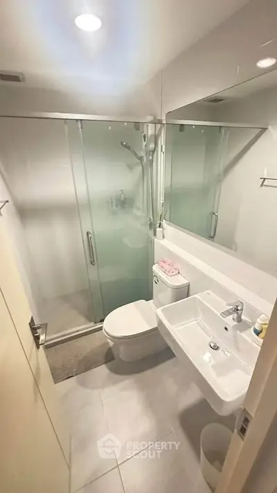 Modern bathroom with glass shower, sleek fixtures, and bright lighting.